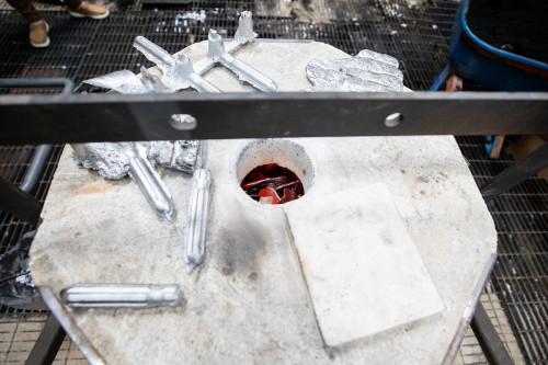 Metal parts are seen sitting on top of a foundry, with flames visible inside.