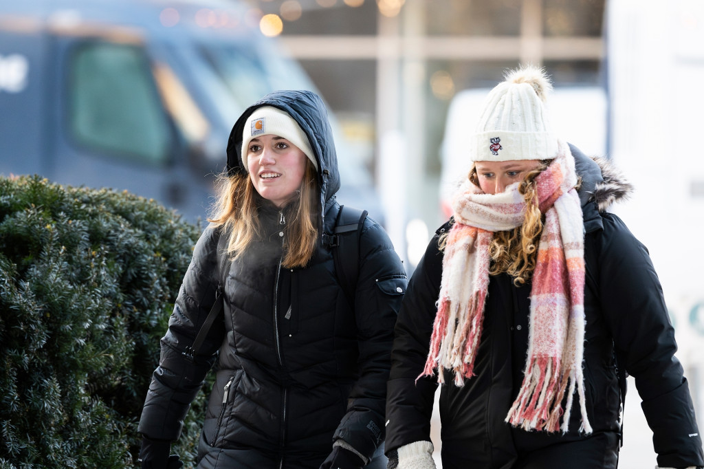 Two people are shown bundled up in winter coats.