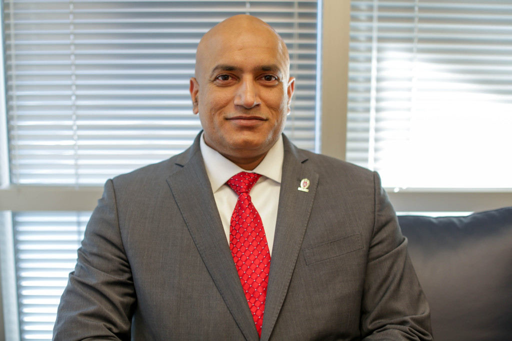 Devesh Ranjan sits for a portrait photo wearing a Wisconsin red tie.