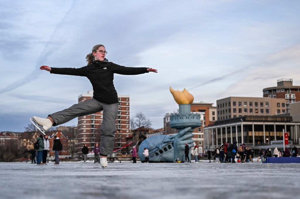 A woman on figure skates holds her arms out and one leg as she spins around on the ice.