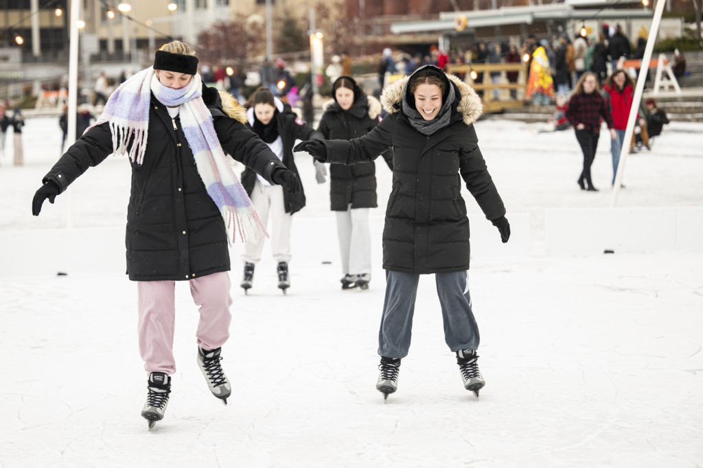 Two women skate on ice.